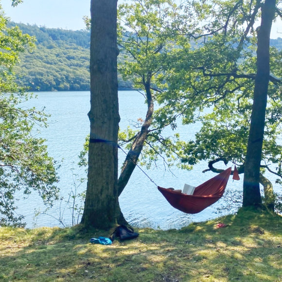 Relaxing in hammock on lakeside campsite.